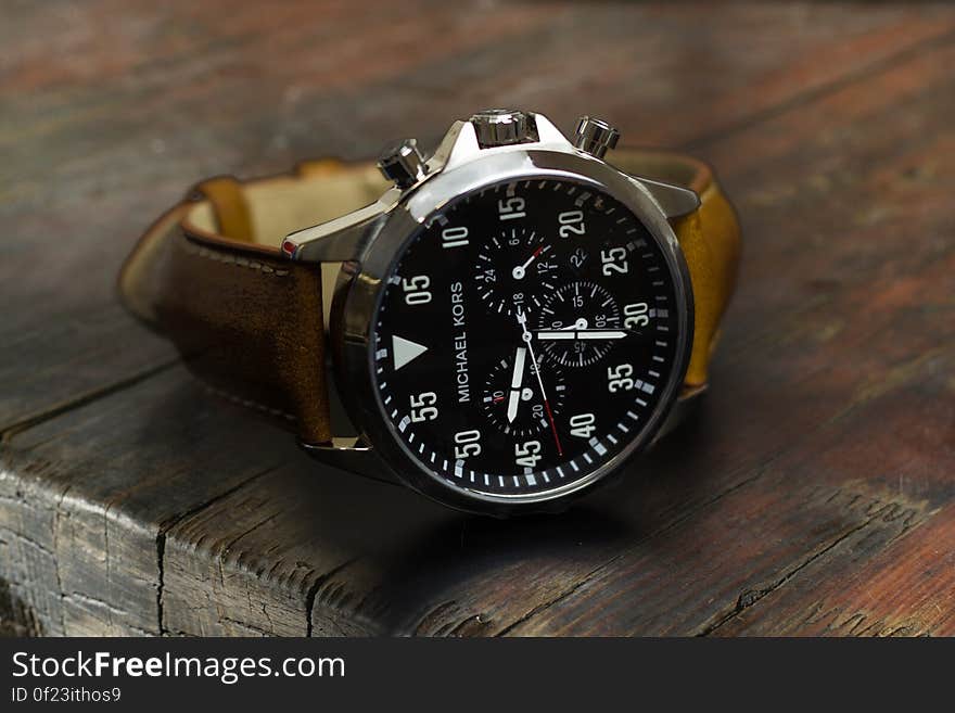 A men's analog watch on a wooden desk. A men's analog watch on a wooden desk.