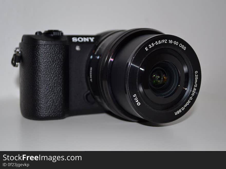 A close up of a black digital camera on a white background.