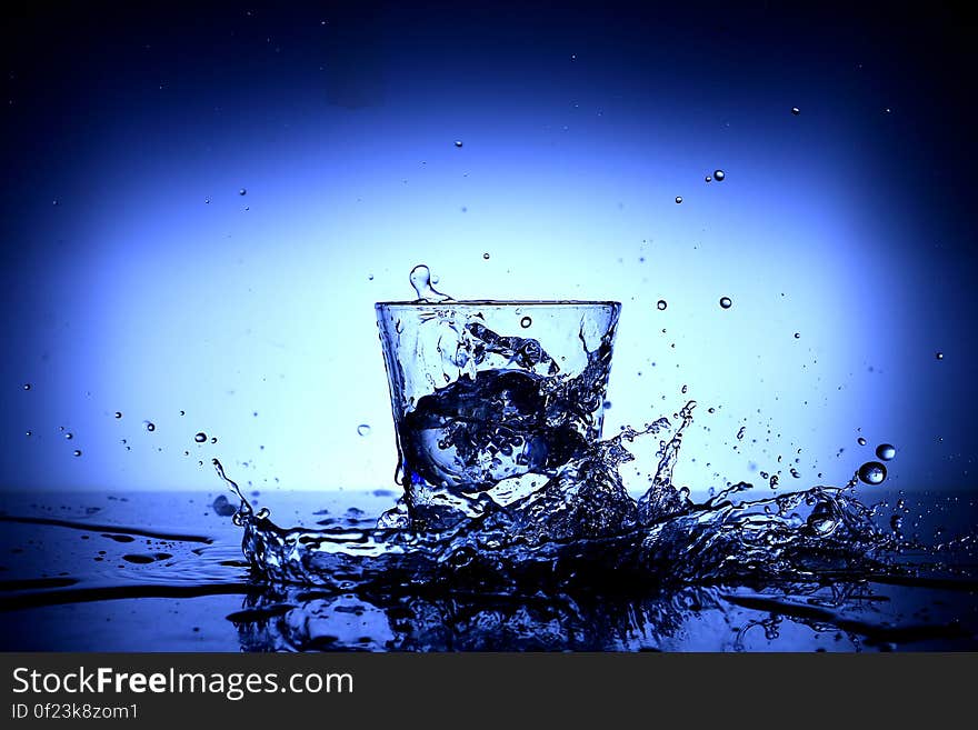 Water splash around a glass on a blue background. Water splash around a glass on a blue background.