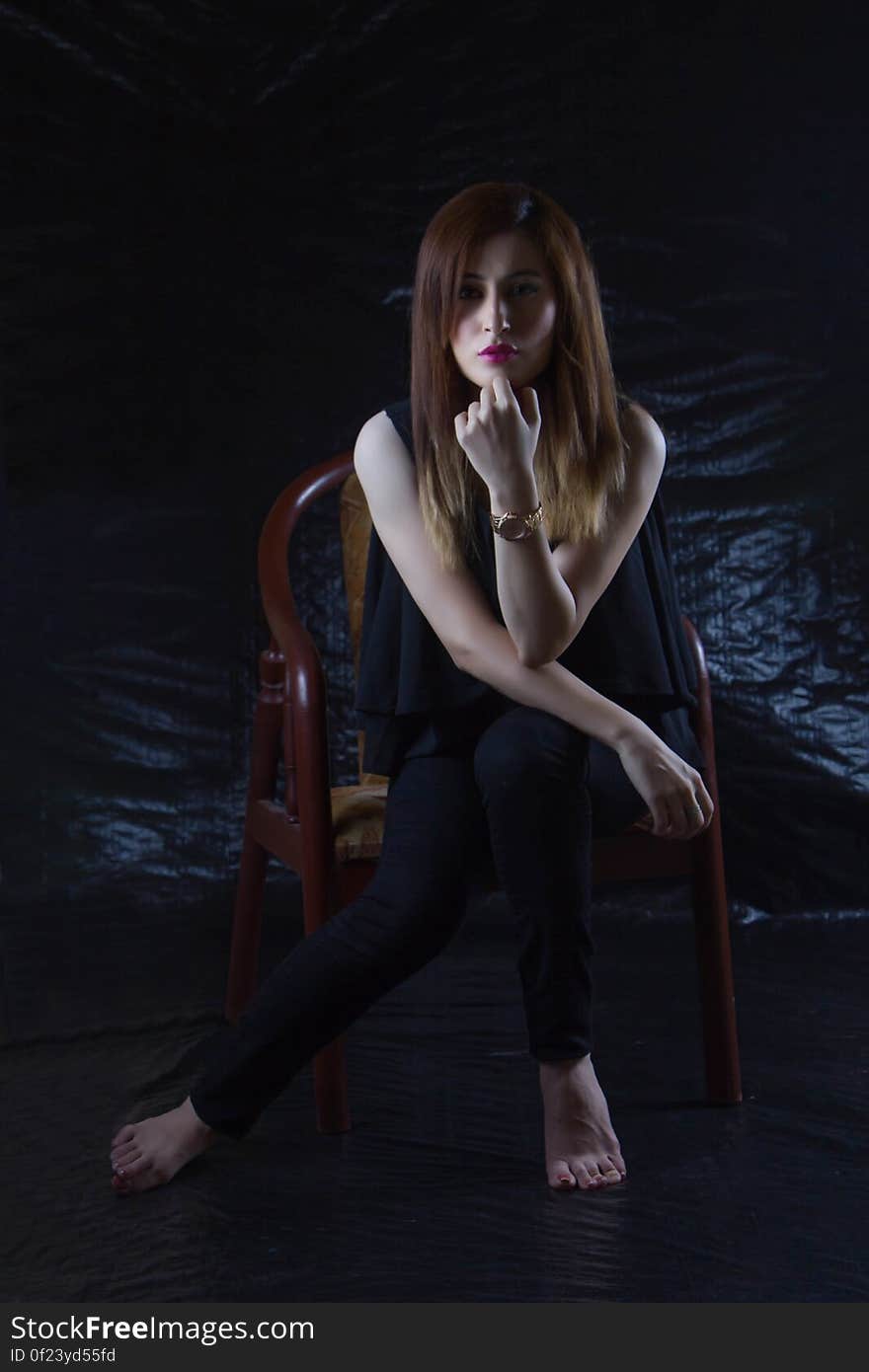 Woman Sitting on Brown Chair With Black Background