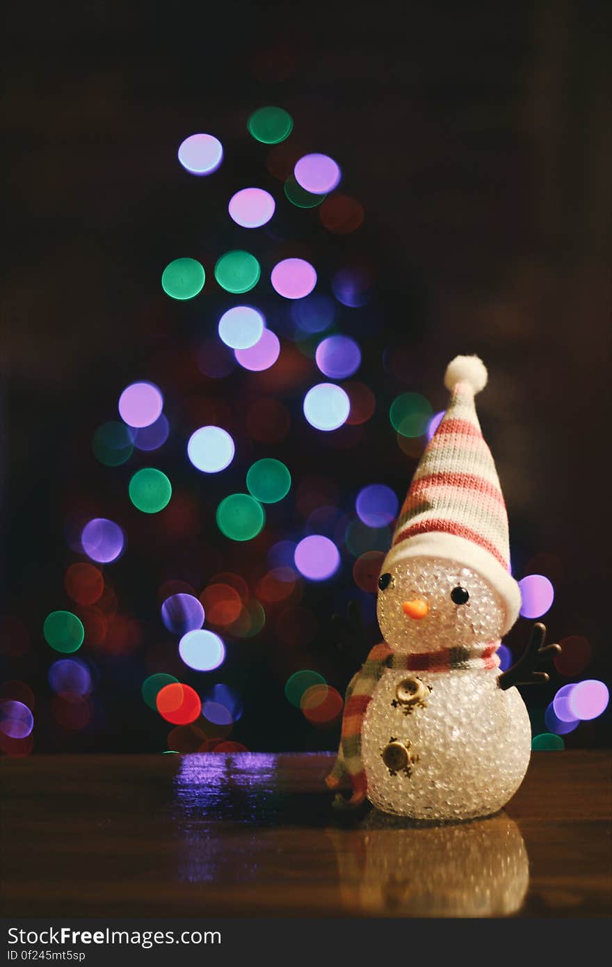 A toy snow man in front of light in the shape of a Christmas tree. A toy snow man in front of light in the shape of a Christmas tree.