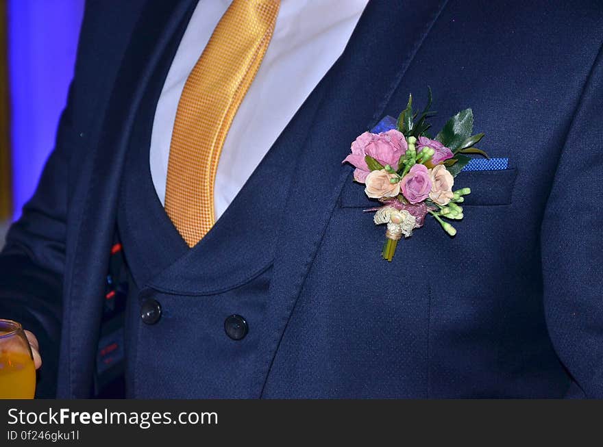 A close up of a wedding lapel pin on groom's dark blue tuxedo.