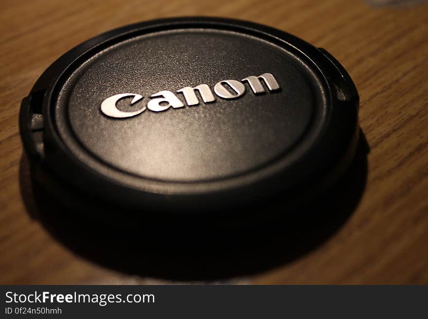 A close up of a camera lens cap on table.