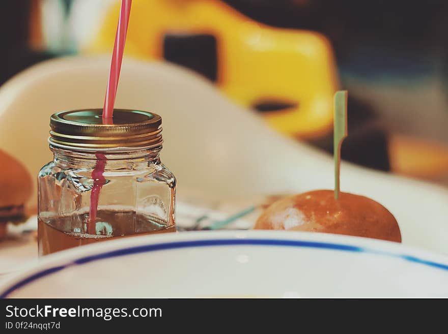 Delicious bun next to a drink in jar with straw. Delicious bun next to a drink in jar with straw.