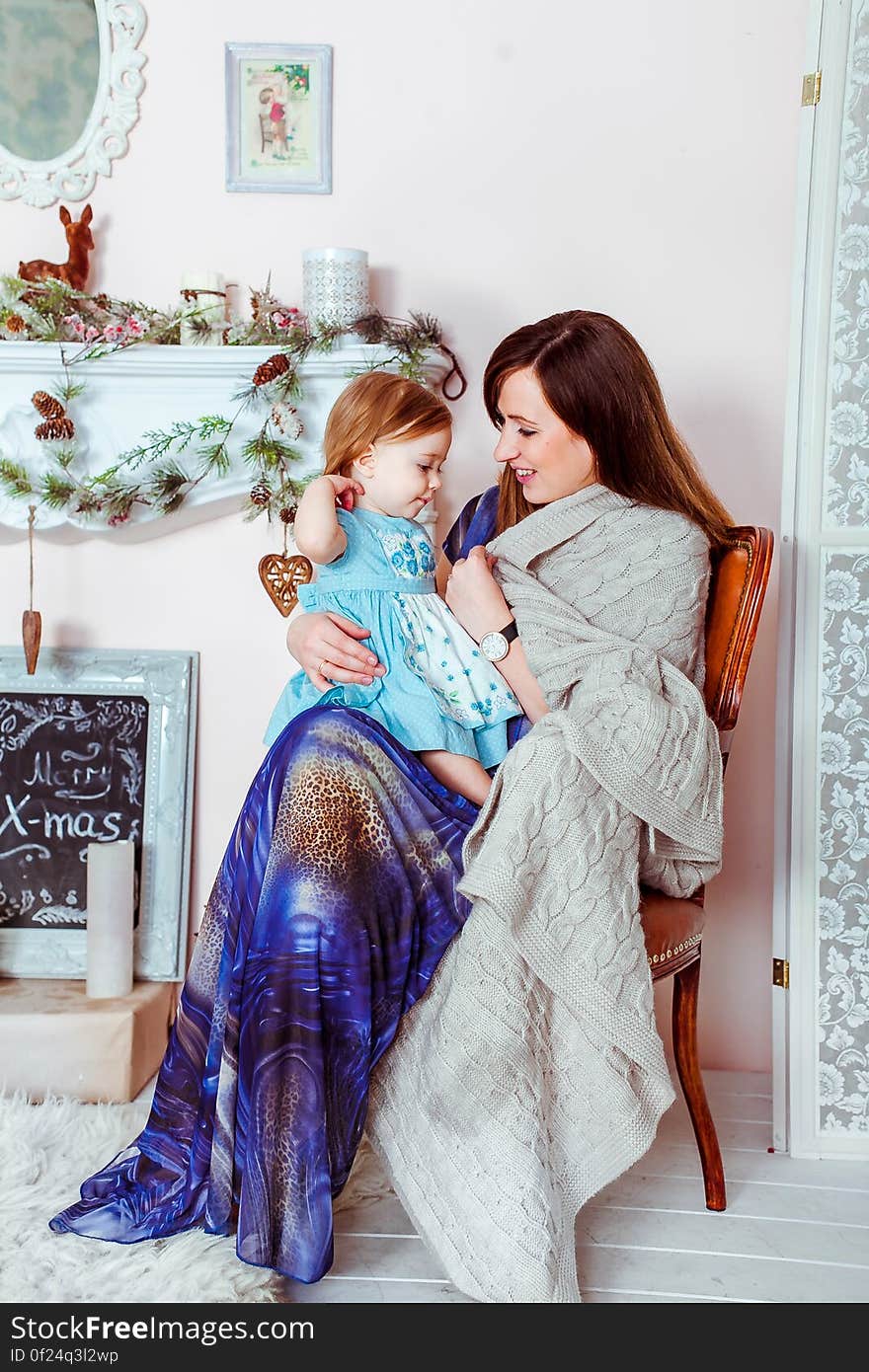 Woman in Blue White and Brown Dress Holding Baby in Teal Dress Inside House