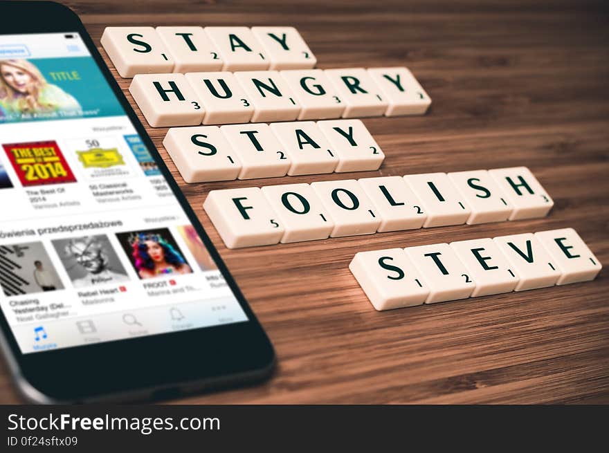 A smartphone with letter blocks forming the quote "Stay hungry stay foolish" accredited to Steve Jobs.