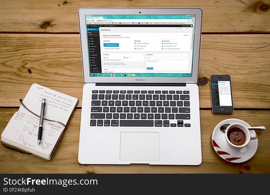 Laptop, smartphone, notebook with a pen and a cup of coffee on a wooden table. Laptop, smartphone, notebook with a pen and a cup of coffee on a wooden table.