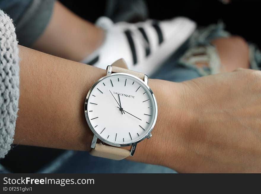 Beige Strap Silver Round Analog Watch Behind Adidas White and Black Superstar