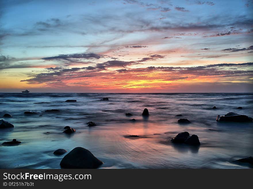 Silhouette of Stones on Seawater during Sunset