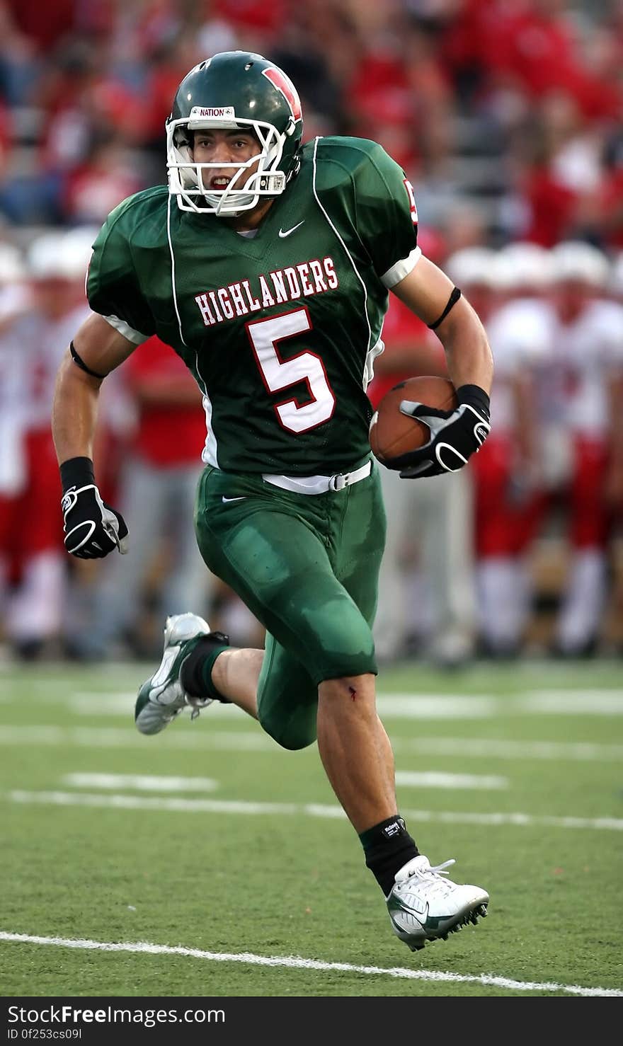 Man Wearing Green American Football Jersey Holding the Ball While Running on the Field