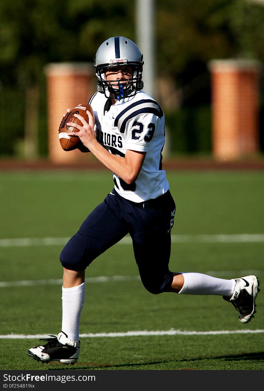 An American football player running on the field with the ball.