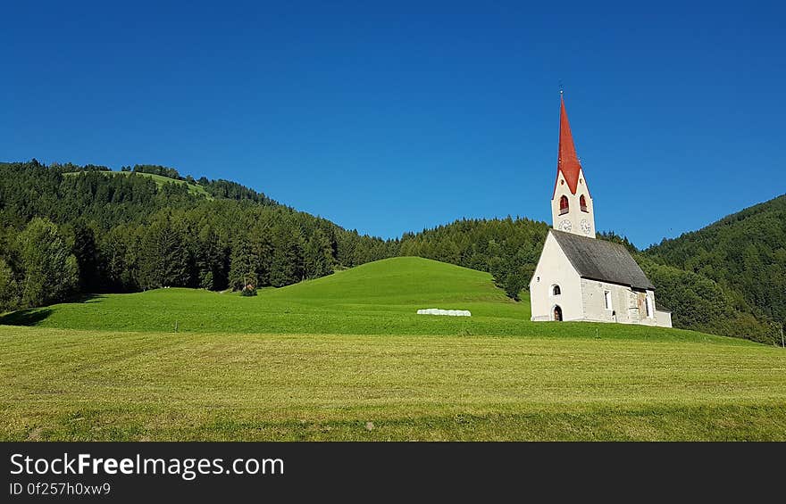 White Gray and Red Chapel on Green Field during Clear Sky Day Time