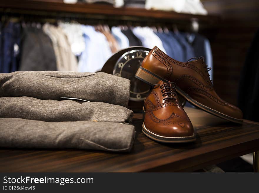 Men`s brown leather shoes and trousers on a shelf in a store. Men`s brown leather shoes and trousers on a shelf in a store.