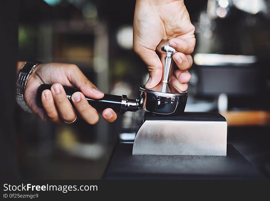 A barista tamping the coffee grounds in the filter before making coffee. A barista tamping the coffee grounds in the filter before making coffee.