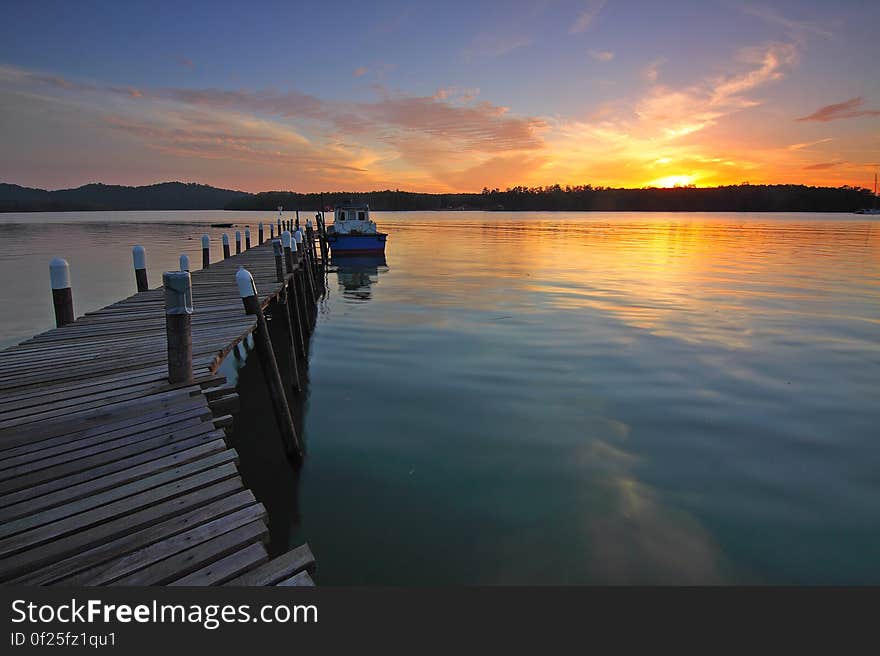 A wooden pontoon and a boat docking at sunset. A wooden pontoon and a boat docking at sunset.