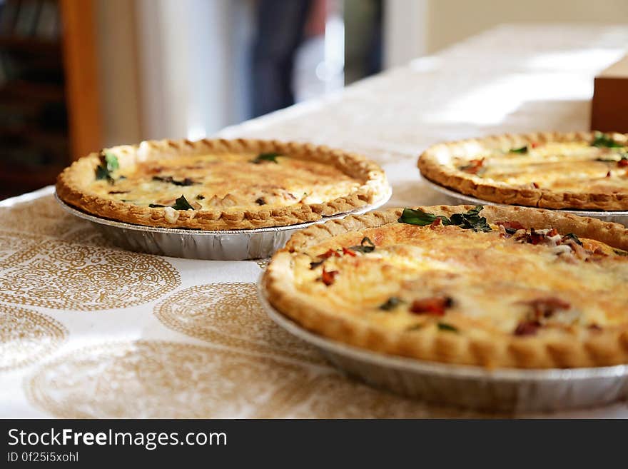 Three freshly baked quiche pies on a table.