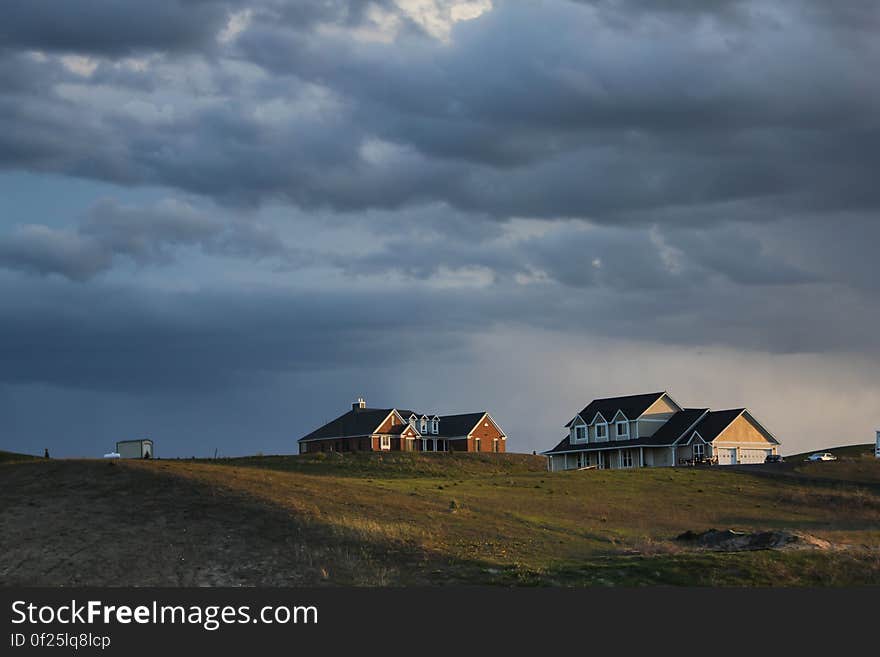 A view of farmland and farm houses under cloudy skies. A view of farmland and farm houses under cloudy skies.