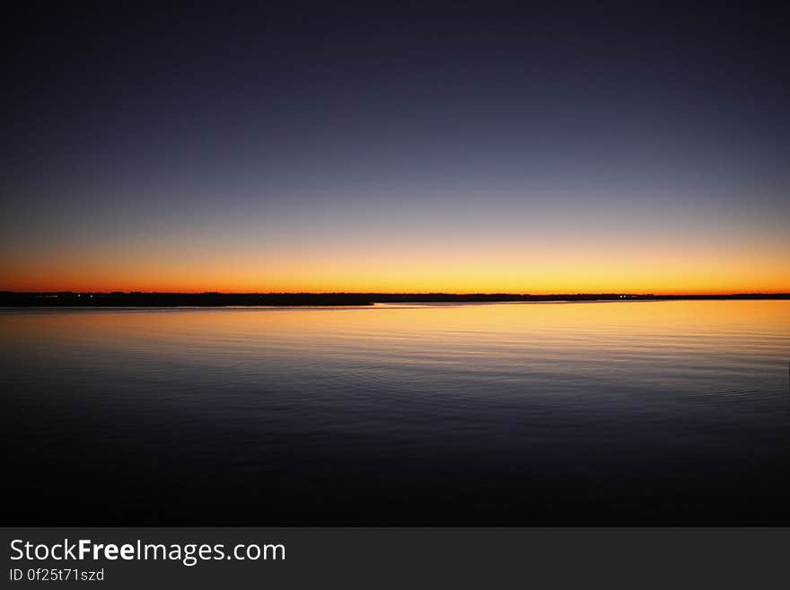 Silhouette of Calm Sea Under Blue and Orange Clear Sky during Sunset