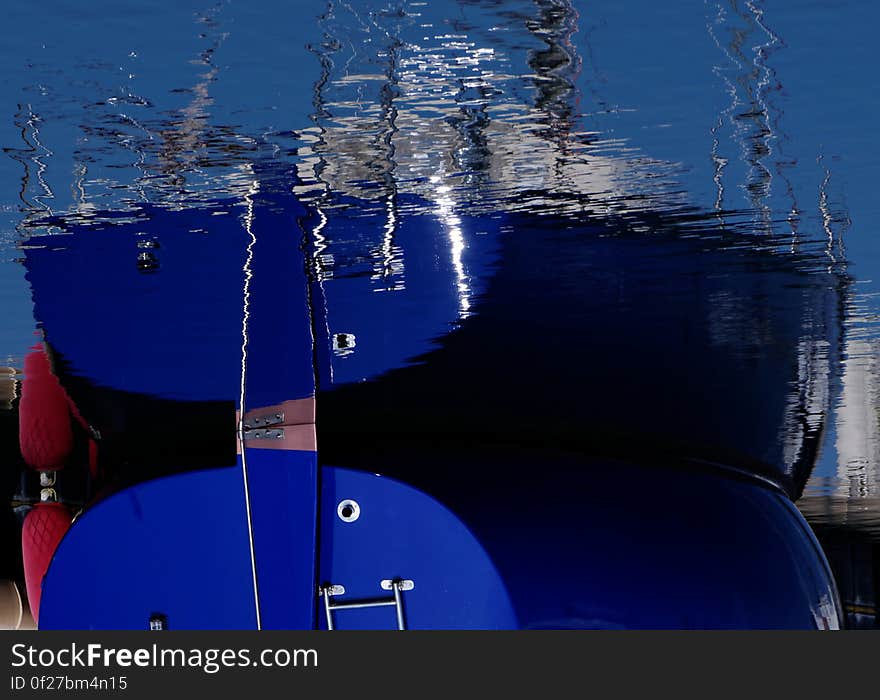 Bow of blue ship reflecting in waters.