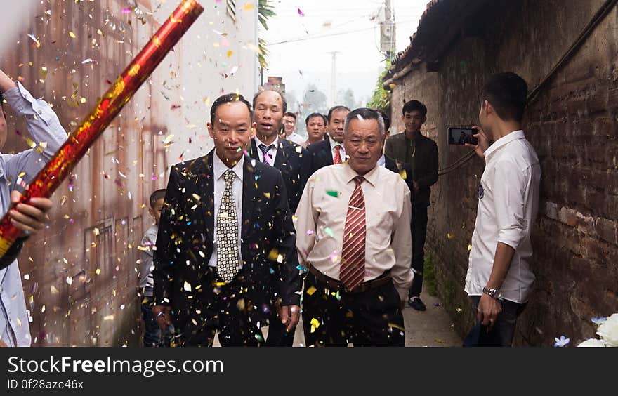 Asian wedding party in alleyway outdoors with confetti.