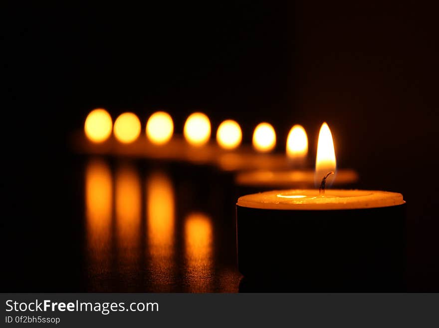 A row of tea light candles in the dark.