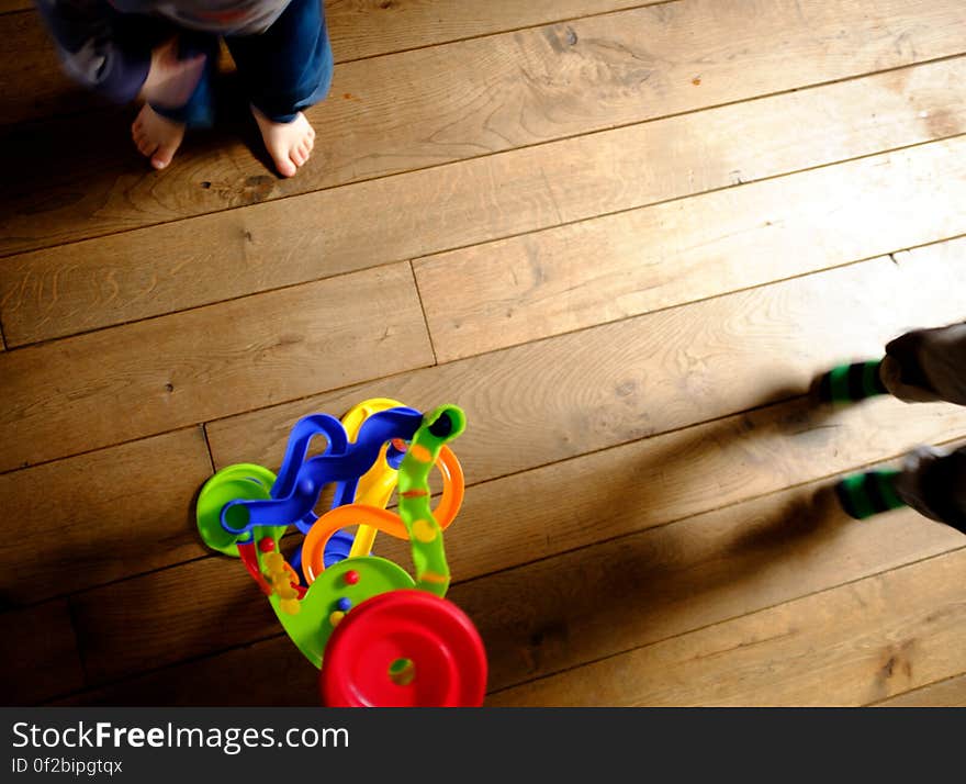 A colorful toy and children's feet on the floor. A colorful toy and children's feet on the floor.