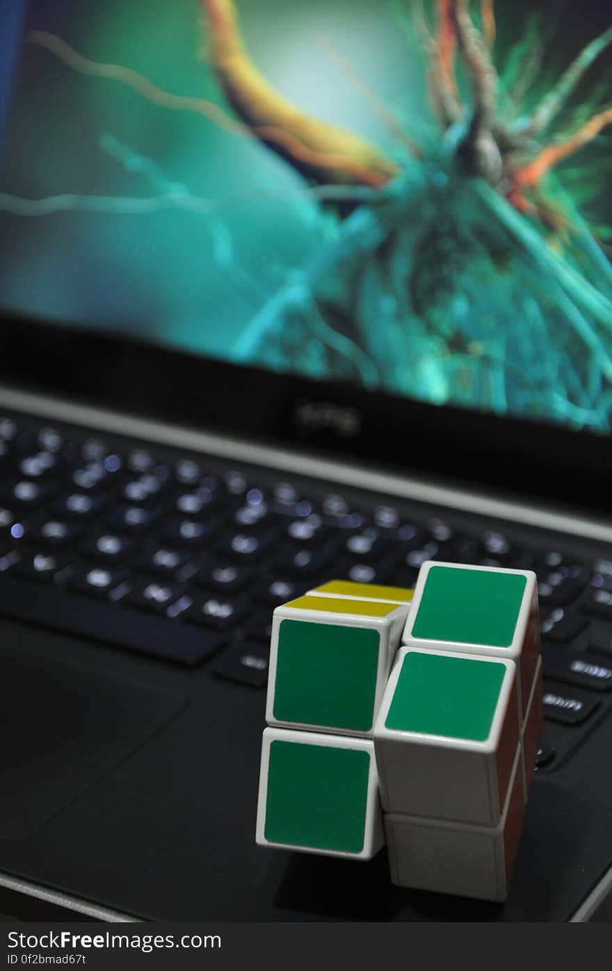 Green and yellow cube toys on laptop computer keyboard with abstract pattern on screen. Green and yellow cube toys on laptop computer keyboard with abstract pattern on screen.