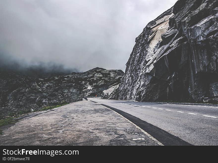 A mountain road beside cliffs in foggy weather.