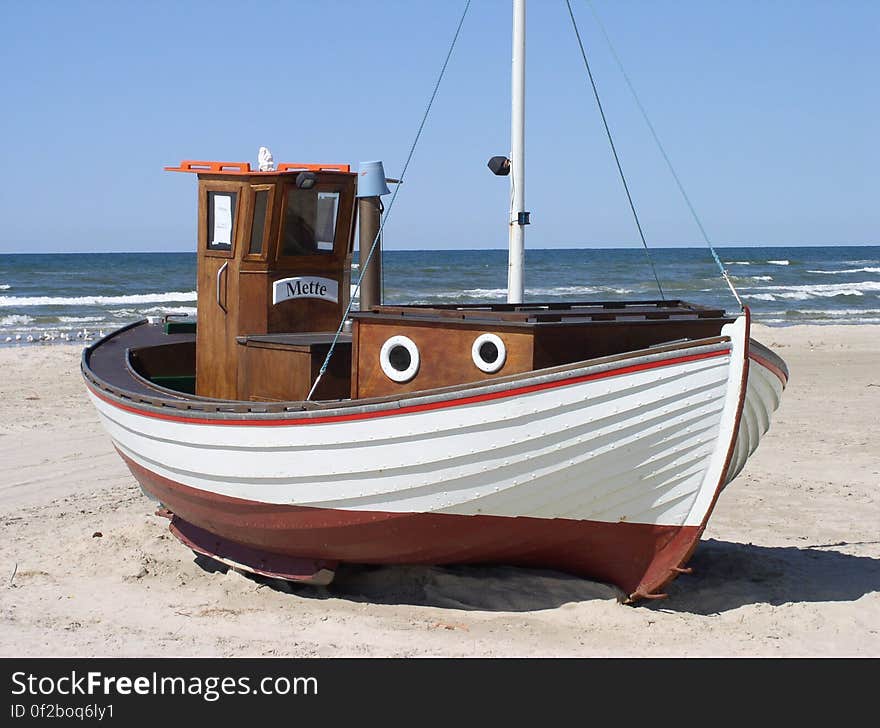 White and Brown Speedboat on White Sand Beside Ocean during Daytime