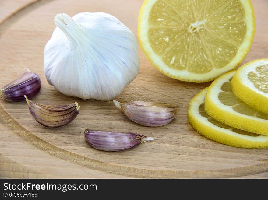 Sliced lemon and whole garlic with cloves on wooden cutting board. Sliced lemon and whole garlic with cloves on wooden cutting board.