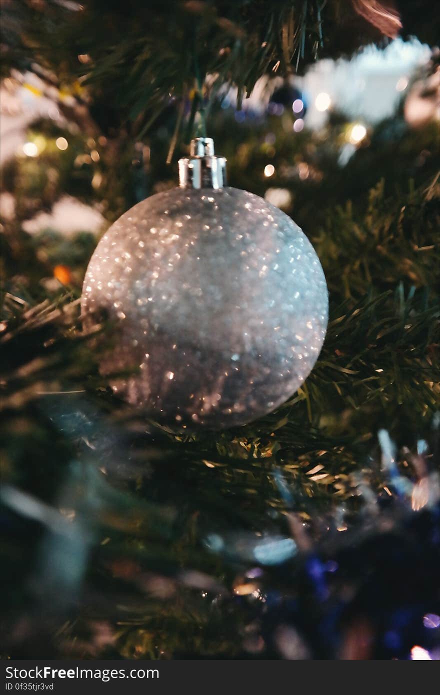 A silver bauble on a green Christmas tree. A silver bauble on a green Christmas tree.