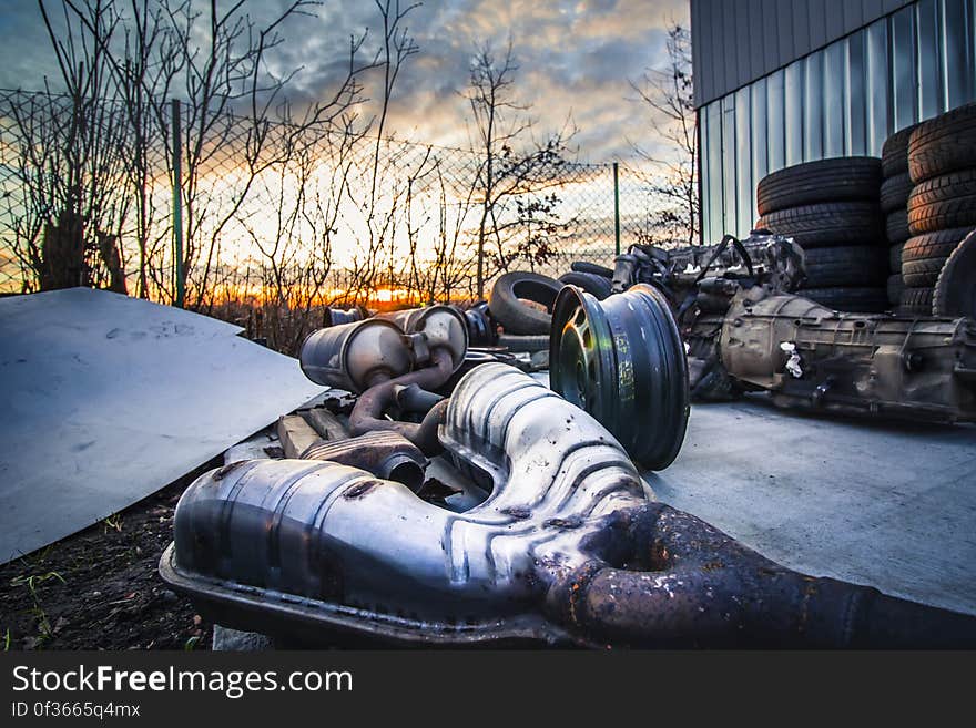 A junk yard with old car parts in the sunset.