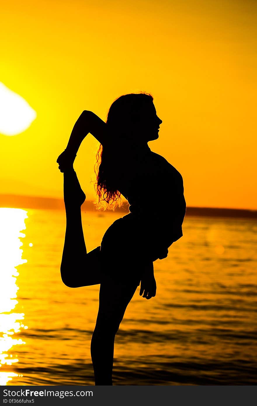 Woman Standing on Beach during Sunset