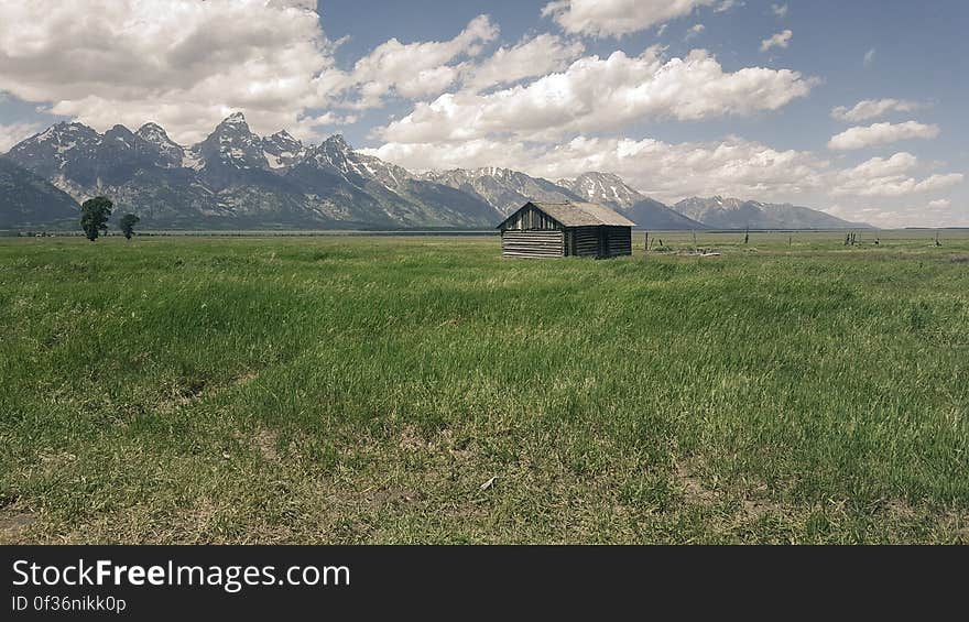 A green mountain field with an old barn. A green mountain field with an old barn.