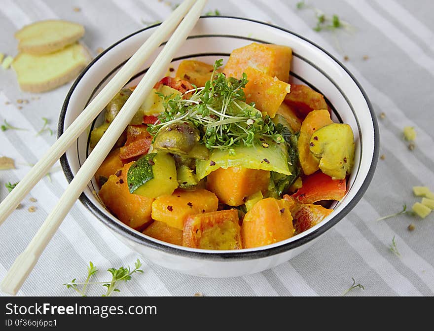 A bowl of cooked vegetables with chopsticks.