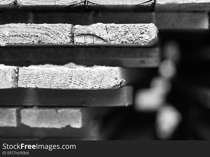 A black and white close up of a pile of wooden planks. A black and white close up of a pile of wooden planks.