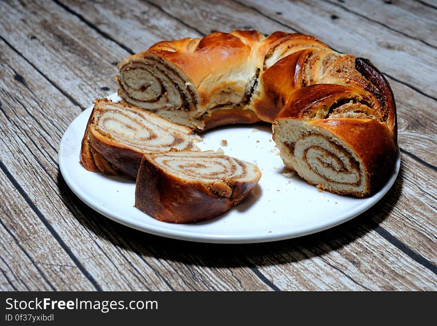 A close up of a homemade bun on a plate on a wooden table. A close up of a homemade bun on a plate on a wooden table.