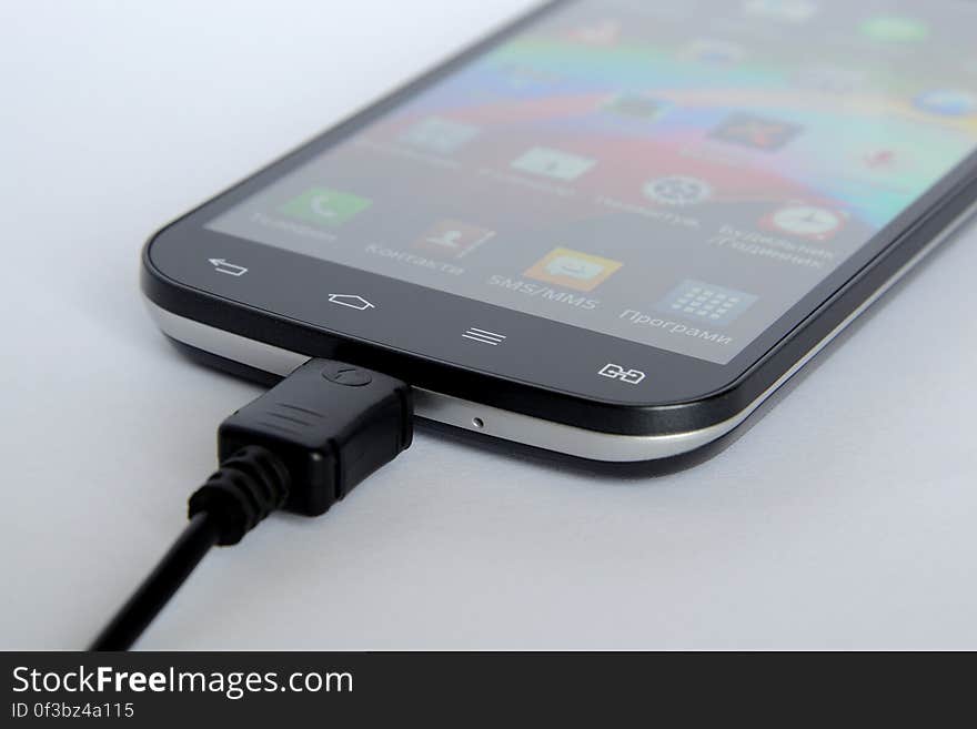 A closeup of a charging smartphone on a table.