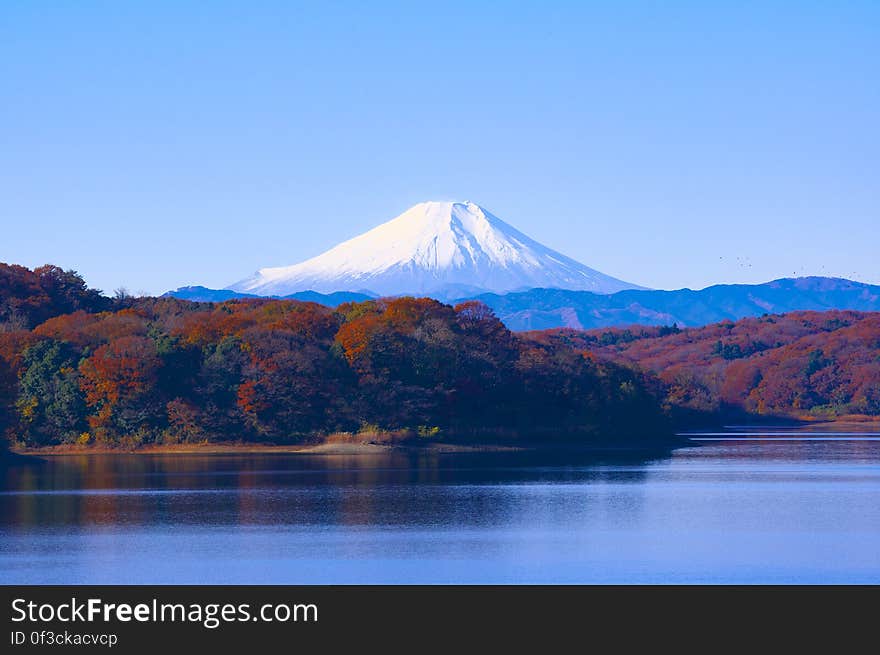 Landscape of fall foliage around alpine lake with snow capped mountains in Japan on sunny day. Landscape of fall foliage around alpine lake with snow capped mountains in Japan on sunny day.