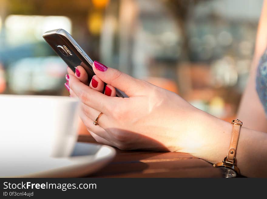 Person Holding a Black Smartphone Wearing a Brown Leather Strap Watch