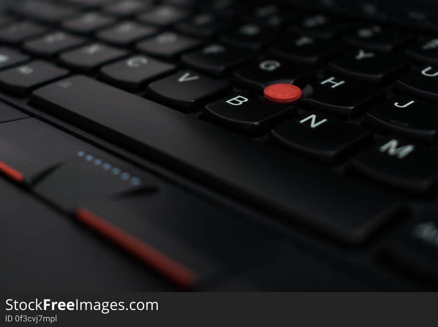 A close up of a laptop keyboard with a trackpoint mouse.