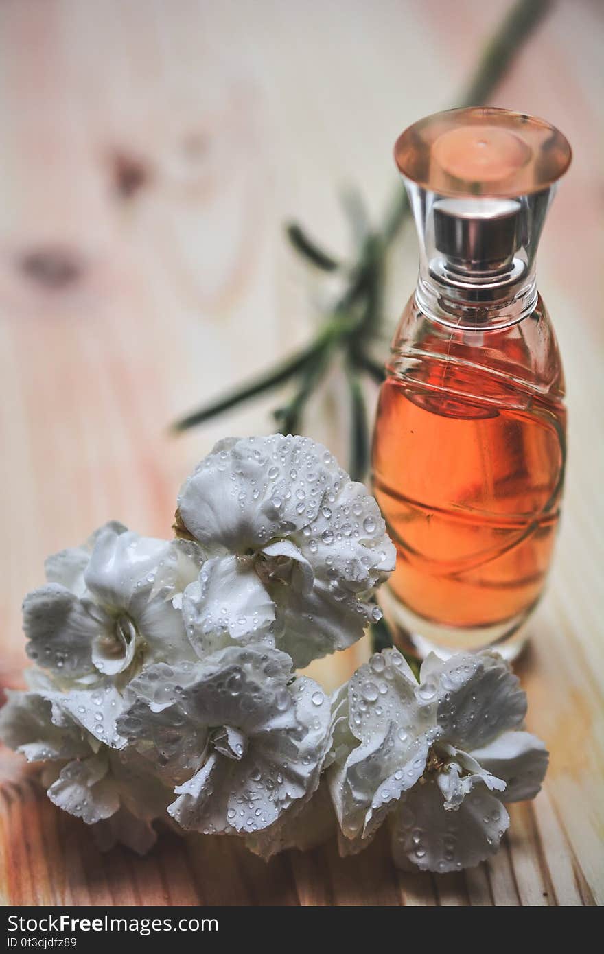 A perfume bottle next to bouquet of flowers.