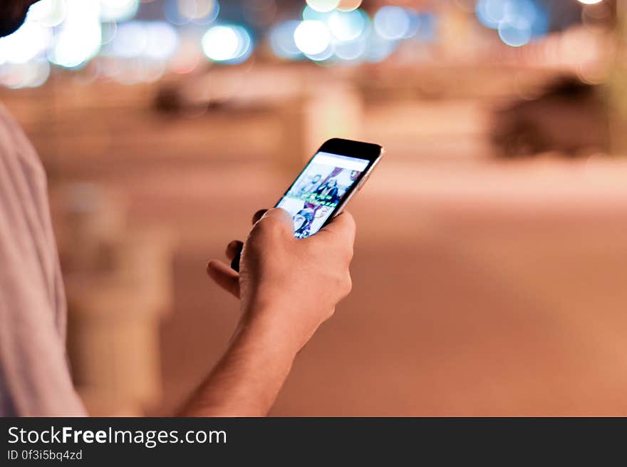 Man Holding and Scrolling a Black Smartphone