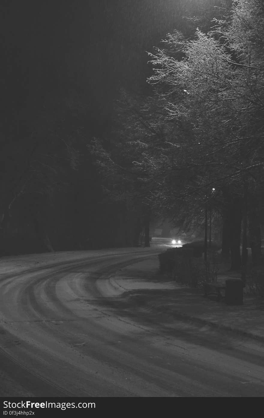 Car driving on curvy snow covered road at night in black and white. Car driving on curvy snow covered road at night in black and white.