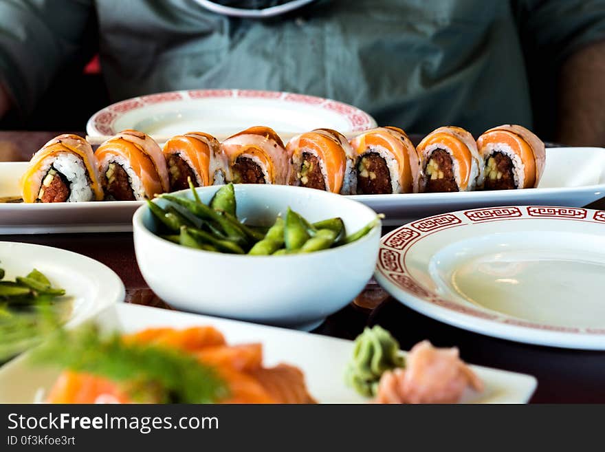 Sushi rolls and other Japanese cuisine on white china plates on tabletop. Sushi rolls and other Japanese cuisine on white china plates on tabletop.