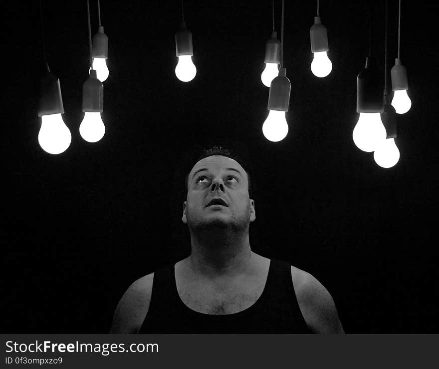 A black and white photo of a man looking at light bulbs. A black and white photo of a man looking at light bulbs.