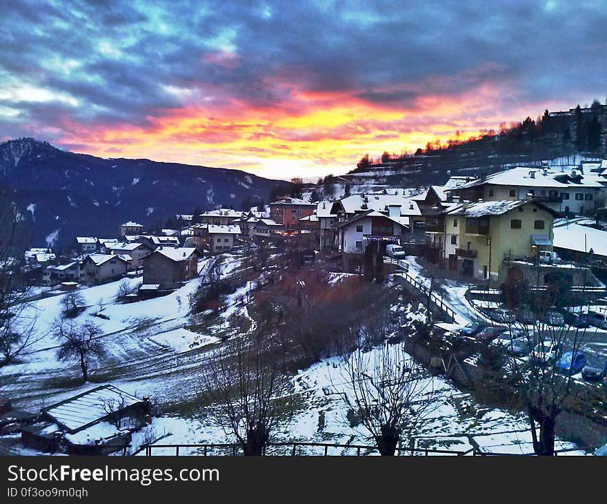 A snowy village with the sun setting in the distance. A snowy village with the sun setting in the distance.