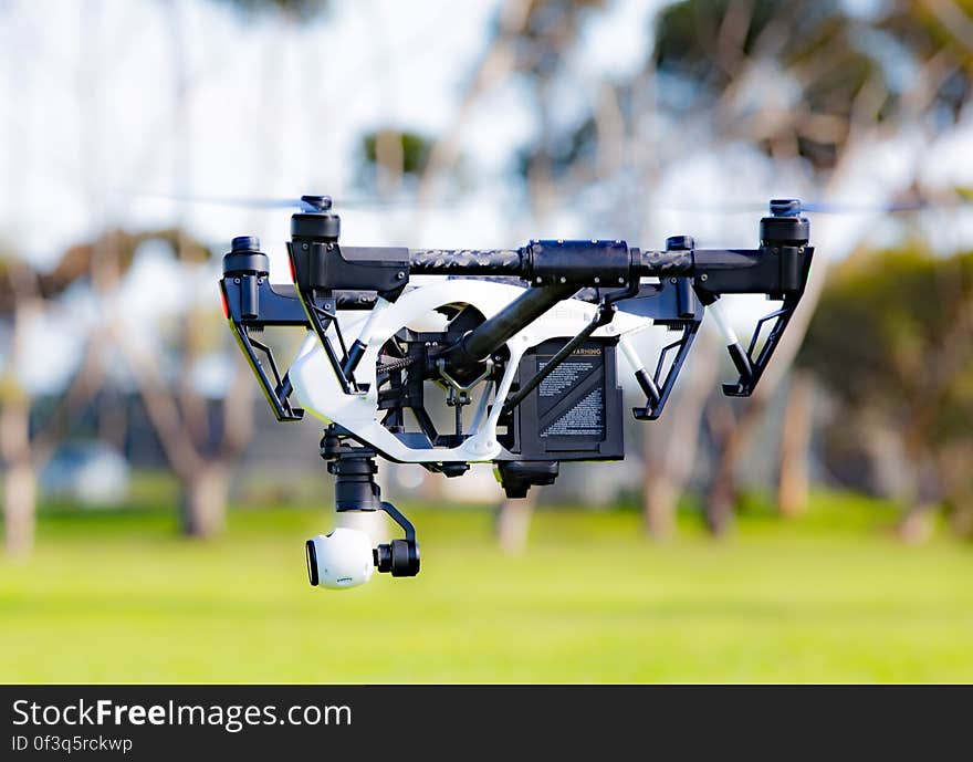 A quadcopter with a camera hovering over green field. A quadcopter with a camera hovering over green field.