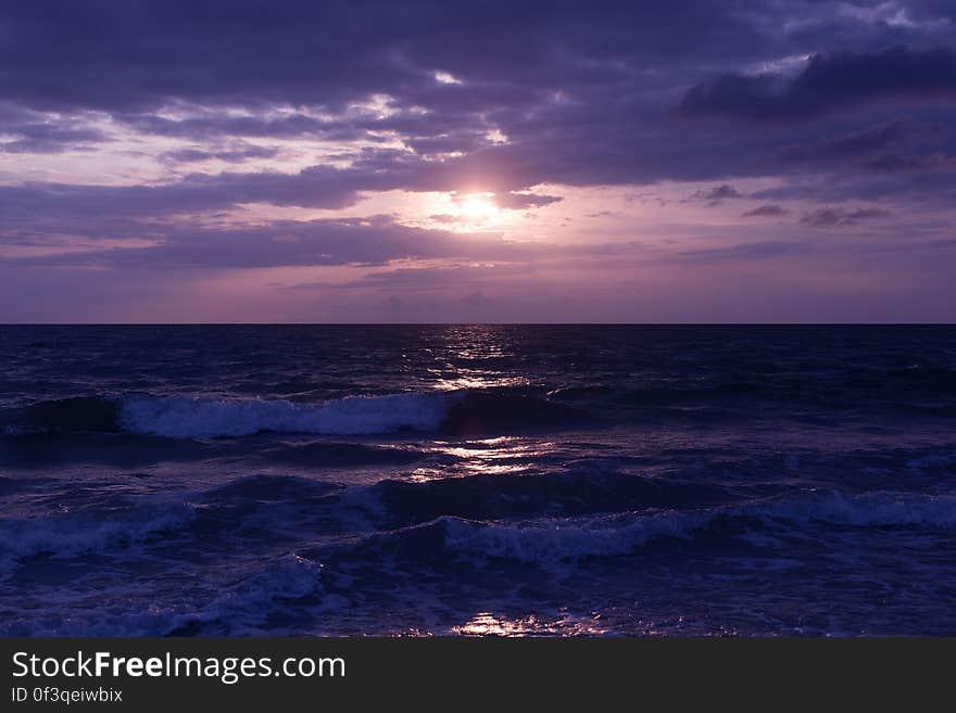 Photo of Blue Ocean and Dark Clouds during Sunset