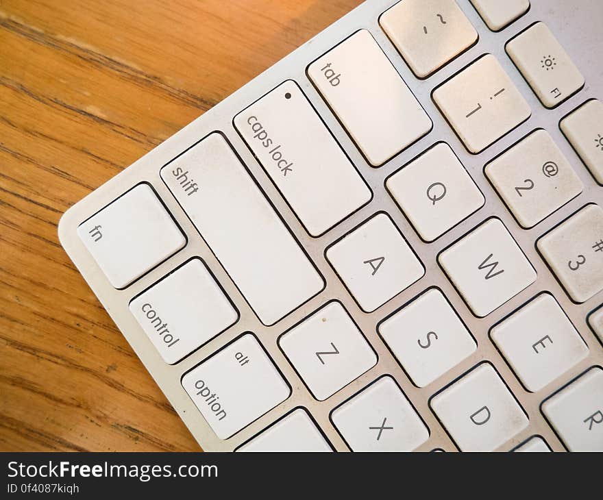 A close up of a white computer keyboard on a wooden background.